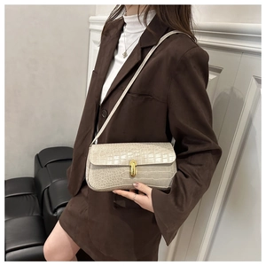 Détail d'un sac beige à motif crocodile avec fermoir capsule doré sur un modèle