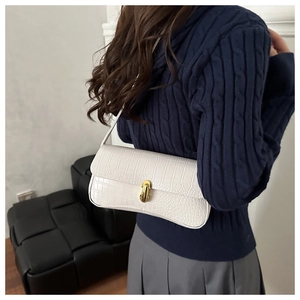 Gros plan du sac baguette blanc avec texture crocodile et fermoir doré élégant