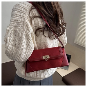 Detail of reddish-brown leather shoulder bag with gold buckle on a model