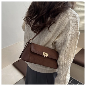 Detail view of brown suede underarm bag on model with gold hardware and shoulder strap