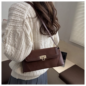 Brown leather patchwork shoulder bag shown worn with a beige sweater in an office setting