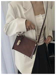Détail du sac bandoulière en daim marron avec fermoir doré tournant et motif matelassé chic