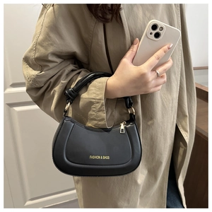 Detailed macro of black half-moon bag featuring gold lettering and knotted strap