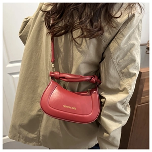 Close-up of a dark red half-moon shoulder bag with gold lettering and smooth finish