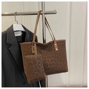 Brown leopard print tote bag with small pouch and studded straps shown on a metal rack