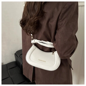 Detail of white half-moon shoulder bag with gold logo and knotted strap on model