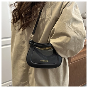 Detail of minimalist black matte leather crossbody bag worn over a khaki winter coat