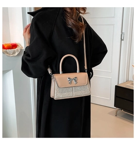 Close-up of beige shoulder bag with silver sequin texture and elegant bow detail