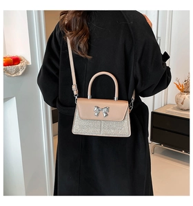 Detail of crossbody bag with silver bow clasp and glitter patchwork on beige leather