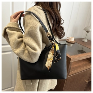 Detail of a large black tote bag with white stitching and a silk scarf on the shoulder