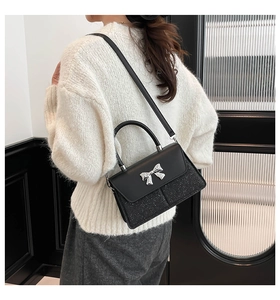 Detail of black crossbody bag with silver bow buckle and glitter texture on model