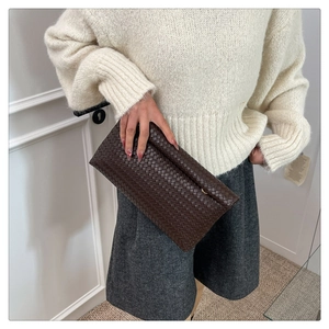 Detail of premium dark brown woven leather clutch handbag with textured grid pattern