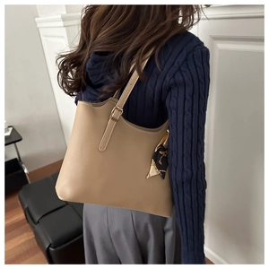 Detail of khaki leather shoulder bag featuring decorative printed silk scarf and metallic buckle