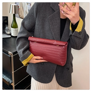 Close-up of red woven leather clutch bag with elegant texture and gold ring hardware