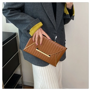 Nahaufnahme einer braunen gewebten Leder-Clutch mit eleganter goldener Metallverzierung