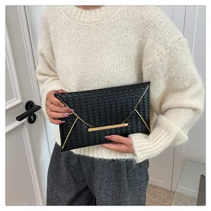 Detail einer schwarzen geflochtenen Leder-Clutch mit eleganten goldfarbenen V-Metall-Details