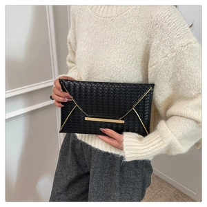 Détail d'une pochette enveloppe en cuir tressé noir avec une bordure dorée élégante