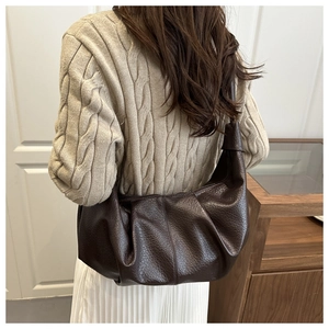 Détail d'un sac bandoulière en cuir PU souple plissé marron foncé avec une forme en demi-lune