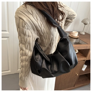 Close-up of black pleated crescent bag with high-quality lychee grain leather texture