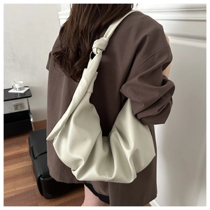 Détail d'un sac hobo blanc cassé en cuir litchi avec bandoulière nouée élégante