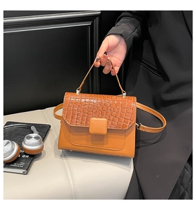Detail of caramel orange crocodile texture flap bag with stylish top handle and strap