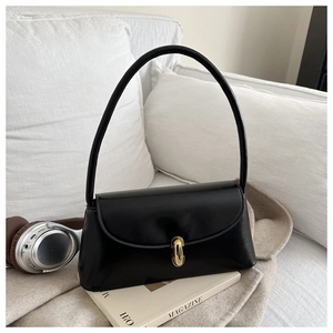 Detail of minimalist black leather shoulder bag with gold clasp on soft white blanket