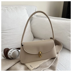 Detail of minimalist beige PU leather underarm bag with a gold metal rotary lock buckle