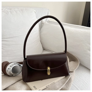Detail of dark brown leather handbag featuring a glossy finish and gold oval metal lock