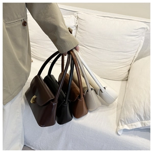 Detail view of five assorted colors of minimalist square shoulder bags with gold twist locks