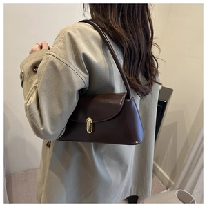 Detail showing deep brown leather shoulder bag with elegant gold U-shaped metal clasp