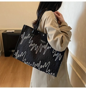 Black quilted tote bag with white wave pattern and New York label on a shoulder model