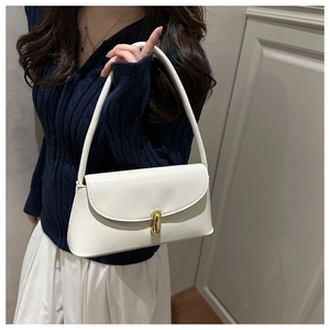 Detail of a creamy white rectangular shoulder bag featuring a gold oval twist-lock closure