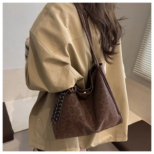 Detail of leopard print tote bag featuring magnetic buckle closure and decorative cord
