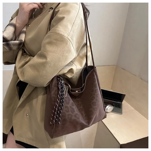 Close-up of brown leopard print tote bag with woven charm and golden logo detail