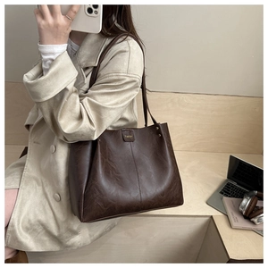 Close-up of dark brown tote bag with vintage texture and Fashion logo on cream coat