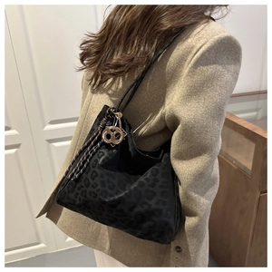 Detail of leopard print tote bag with gold logo charm and tassel on shoulder strap