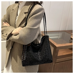 Detail of black leopard print suede tote bag with woven tassel charm on shoulder