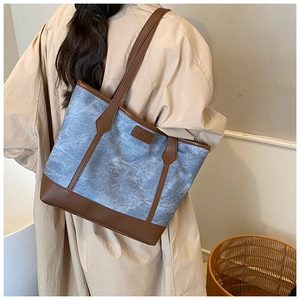 Dettaglio della borsa tote in denim blu con finiture in pelle e logo FASHION