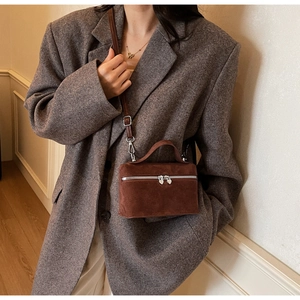 Détail du mini sac boîte en daim marron foncé avec fermetures éclair coeur sur le mannequin