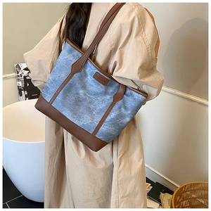 Detail of blue textured canvas tote with brown leather straps and fashion label