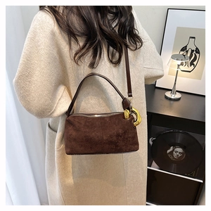 Détail d'un sac cylindre en daim marron avec boucle en métal doré et bandoulière chic