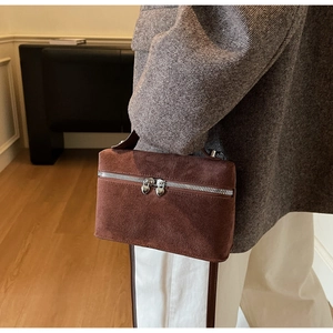 Detail einer braunen Wildleder-Box-Tasche mit herzförmigen Metallreißverschlüssen im Retro-Stil