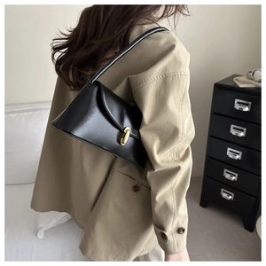 Close-up of a black patent leather shoulder bag with a gold metal twist lock closure