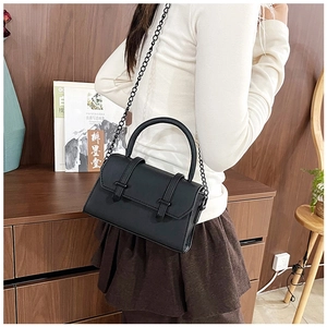 Detail shot of a black minimalist leather crossbody bag with metal chain strap