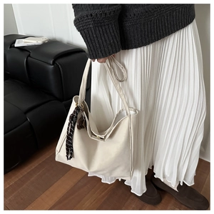 Detail of cream suede tote bag with brown plaid scarf and soft minimalist texture