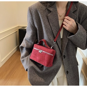 Detail of red suede mini box bag featuring heart-shaped zipper and silver hardware