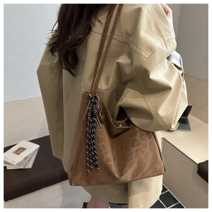 Détail du sac cabas vintage en daim marron avec motif léopard et pendentif tressé