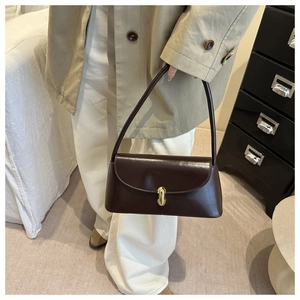 Detail of dark coffee patent leather baguette bag with a golden oval twist lock