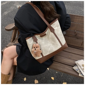 Detail view of the vintage canvas tote bag with brown leather trim and bear pendant