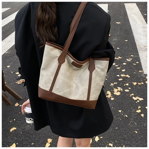 Elegante borsa tote in tela beige con finiture in pelle marrone indossata da una modella